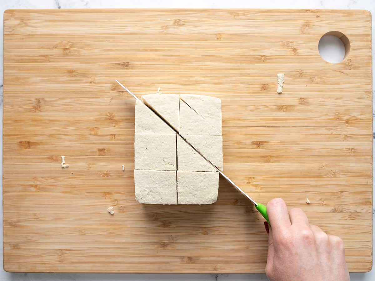 A block of tofu being sliced into triangles