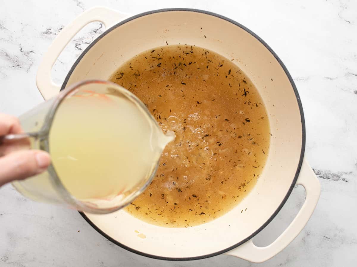 Overhead shot of chicken stock being poured into soup base.