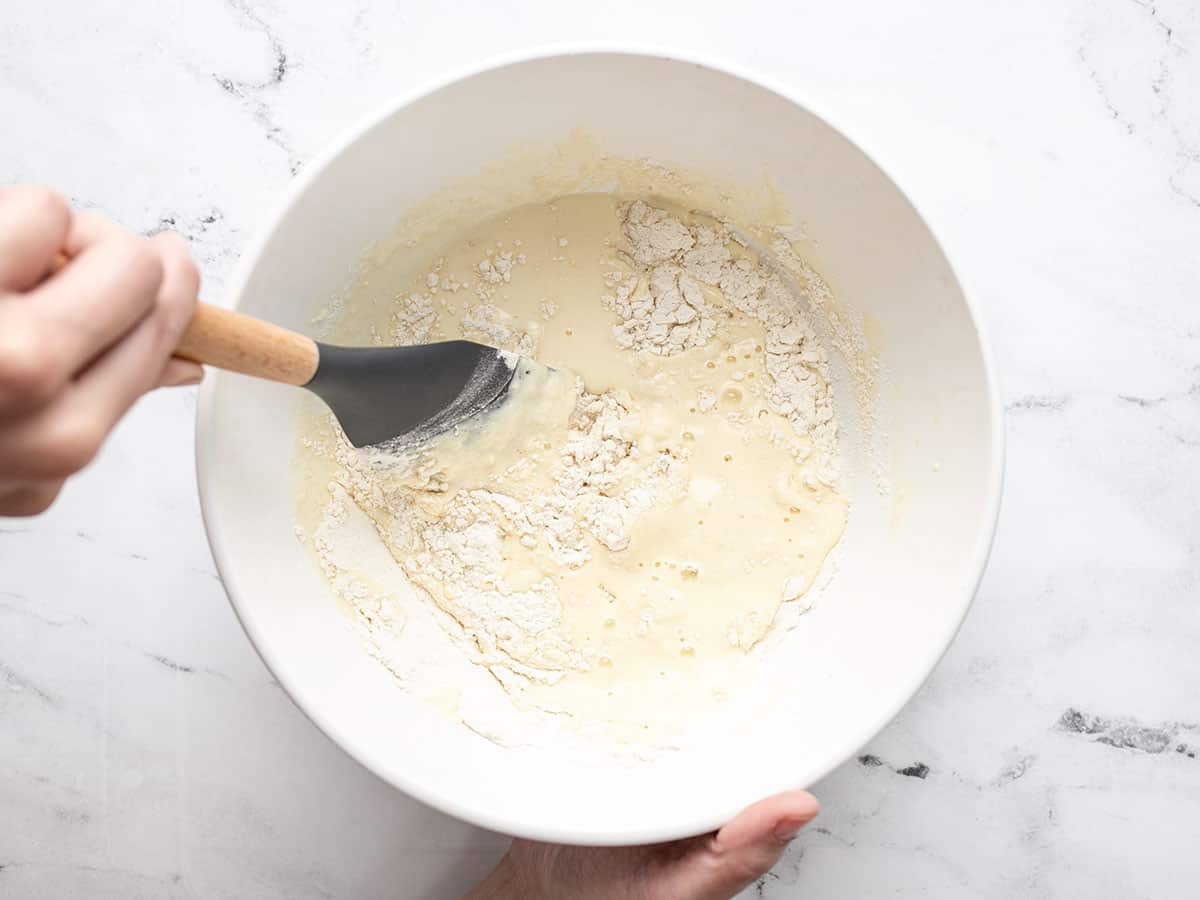 Overhead shot of wood handled rubber spatula mixing wet and dry ingredients.