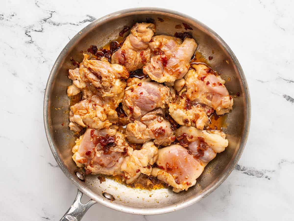 Chicken thighs cooking in a skillet.