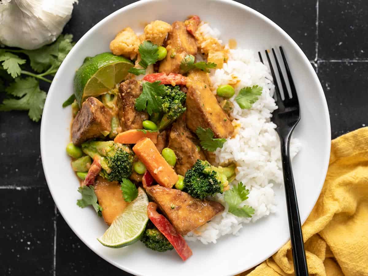 Overhead view of a bowl full of peanut tofu and rice with a black fork.