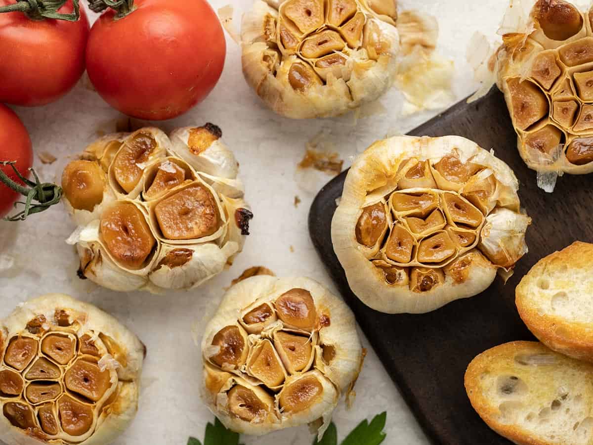 Several heads of roasted garlic scattered on a surface.