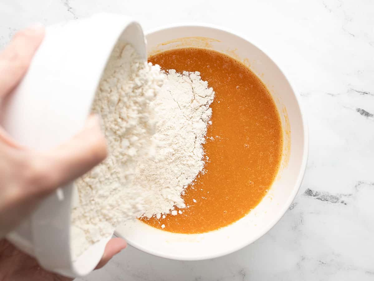 Overhead shot of dry ingredients being dumped on top of wet ingredients.