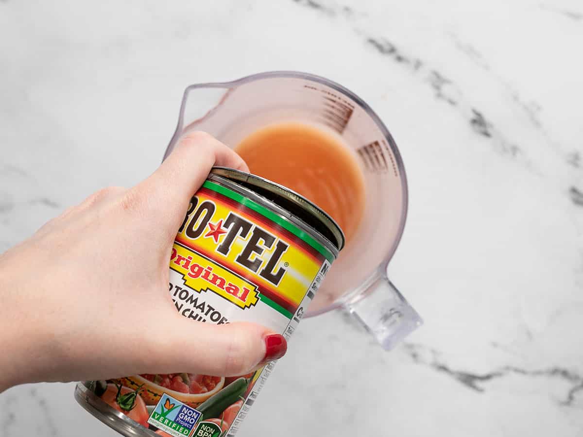 Rotel tomatoes being drained into a measuring cup.