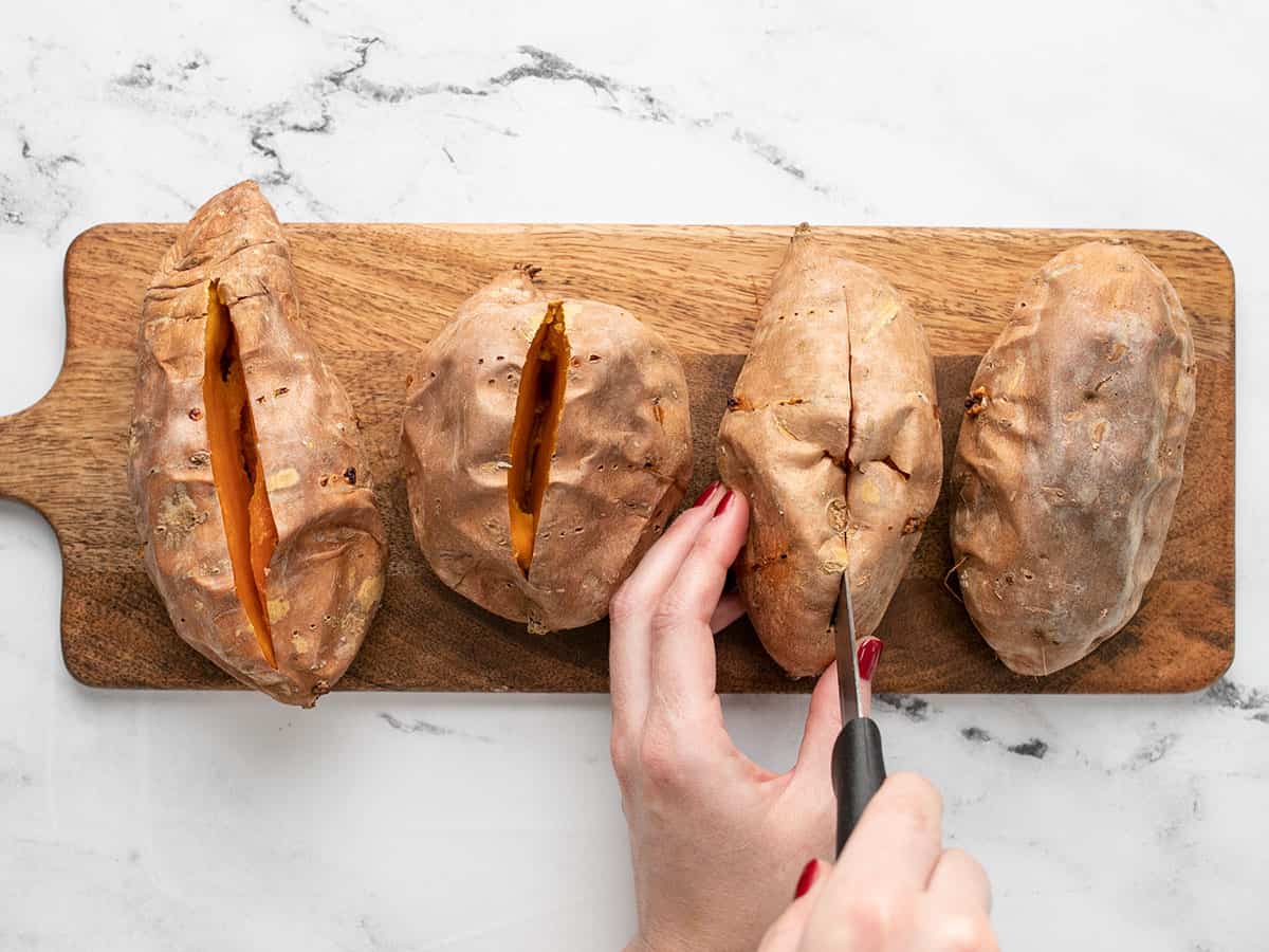 Sweet potatoes being sliced open with a knife. 