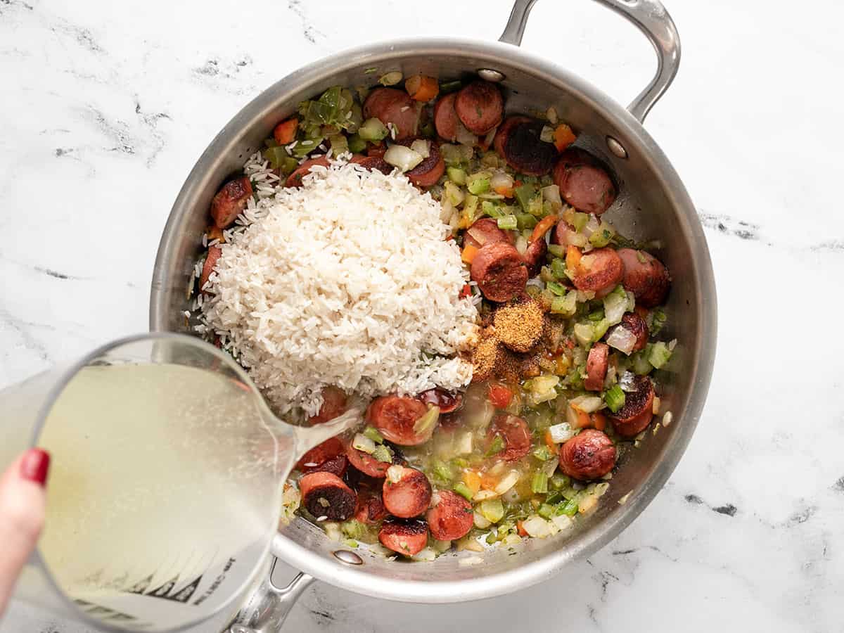 Rice, broth, and seasoning added to the skillet.