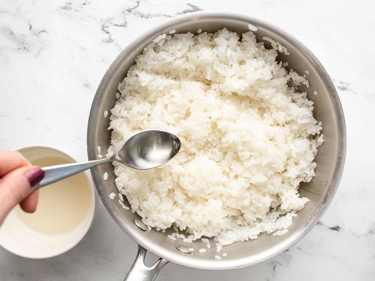 Seasoning being drizzled over the rice in the pot.