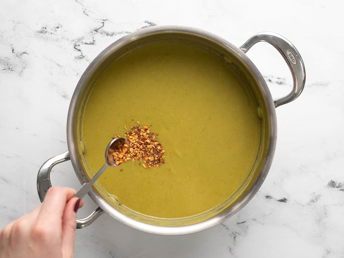 Steak seasoning being added to the soup.