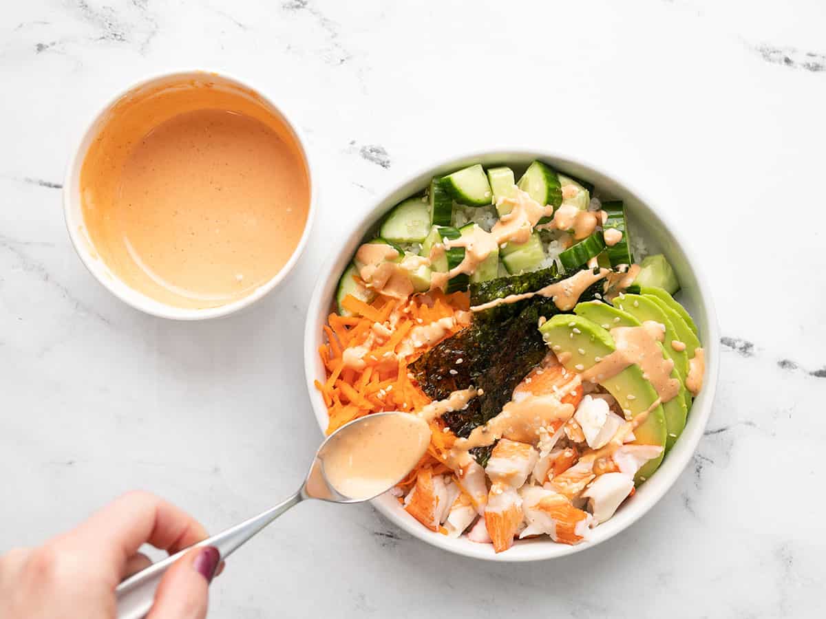 Sriracha mayo being drizzled over the sushi bowl.