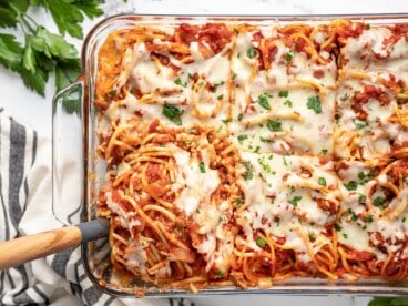 Overhead view of baked spaghetti being scooped out of the casserole dish.