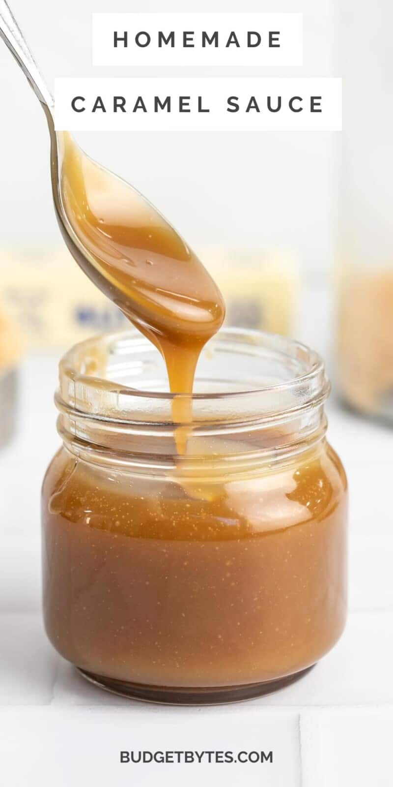 Side shot of a spoon drizzling caramel sauce in a mason jar.