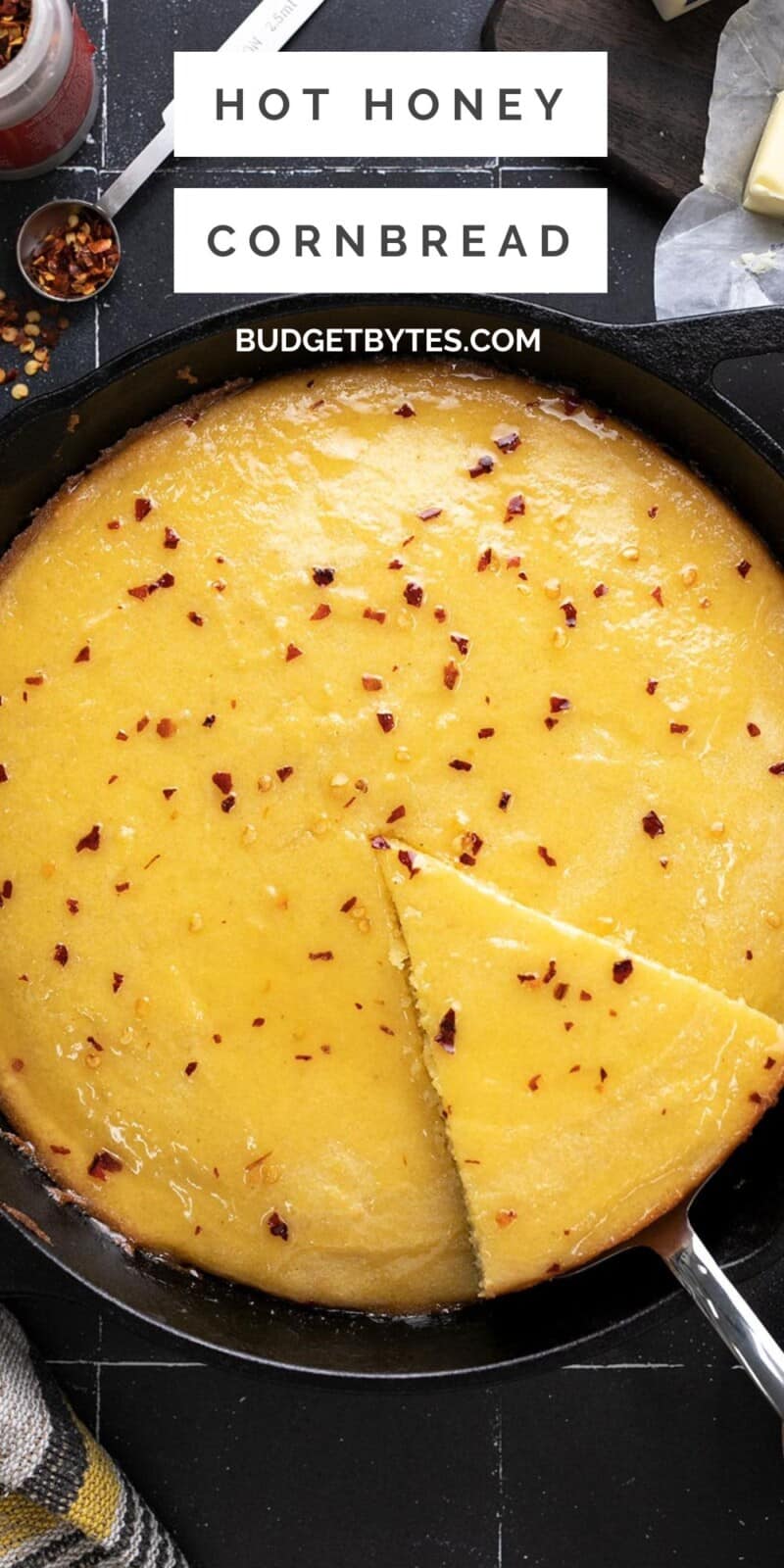 Overhead shot of hot honey cornbread in a cast iron skillet with a wedge being taken out.