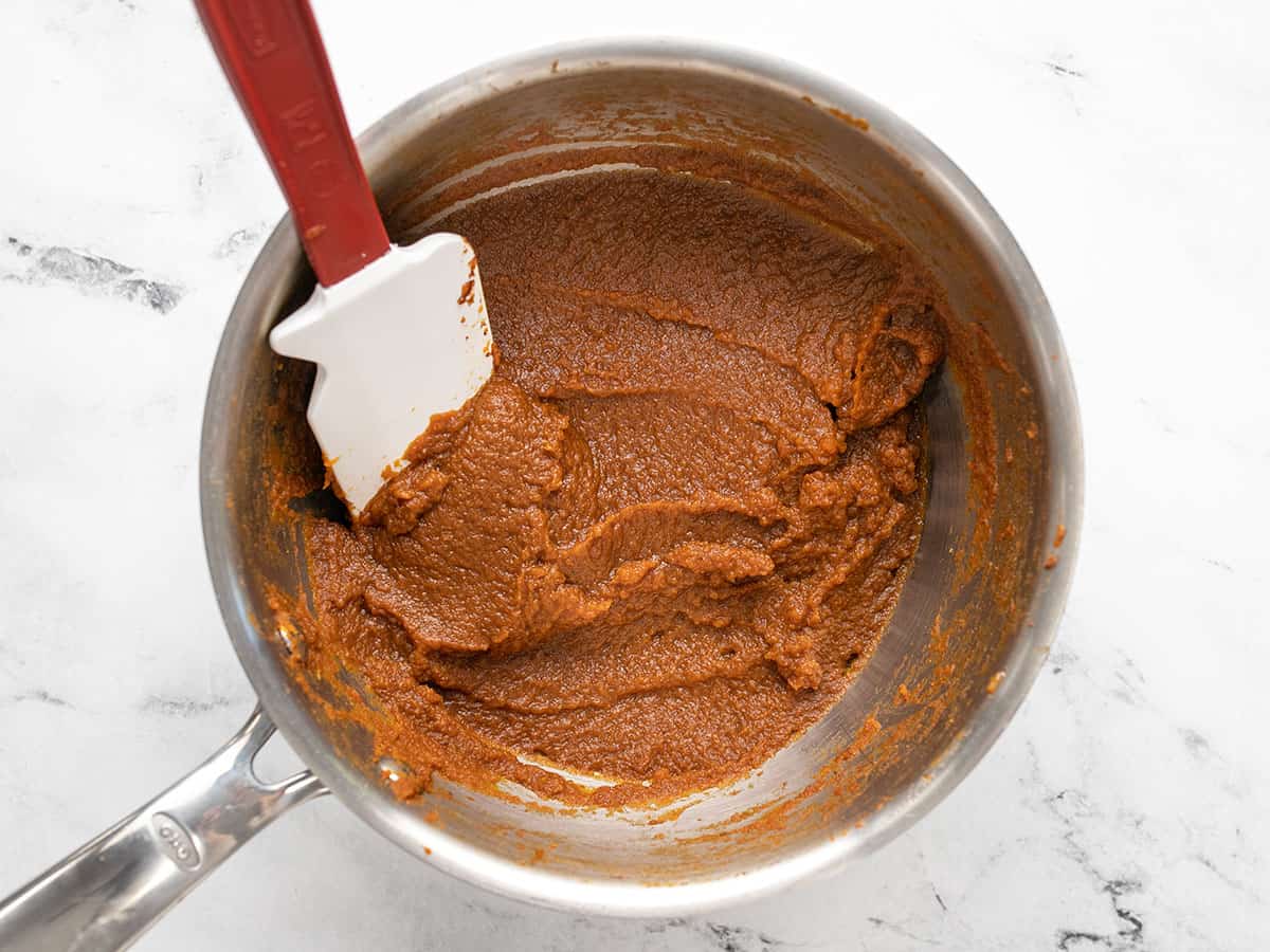 Cooked pumpkin purée, sugar, and spices in a pot. 