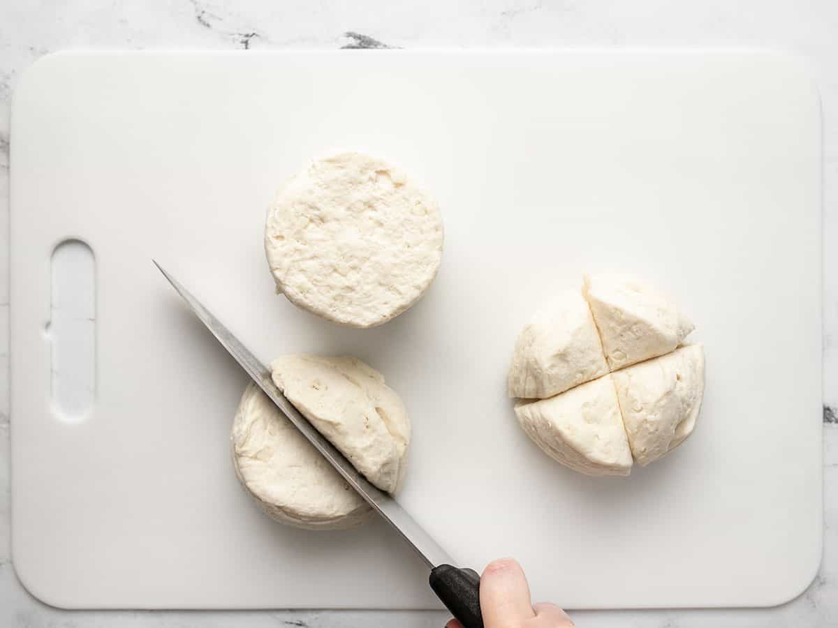 Overhead shot of knife cutting canned biscuit rounds.