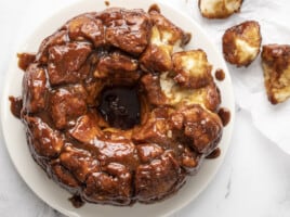 Overhead shot of monkey bread on white plate with a few pieces picked out of it .