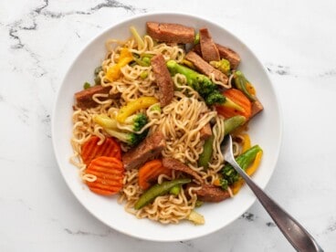 Overhead view of a bowl of spam stir fry noodles with a fork.