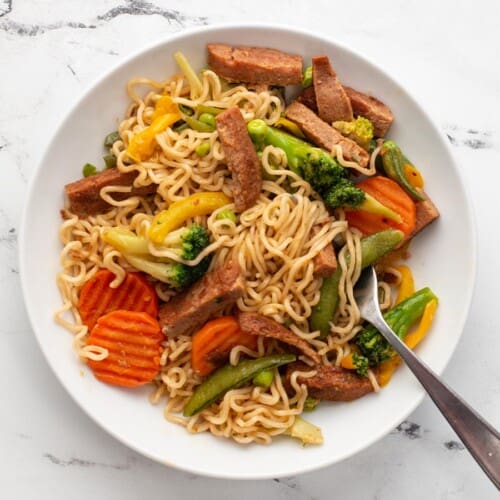 Overhead view of a bowl of spam stir fry noodles with a fork.