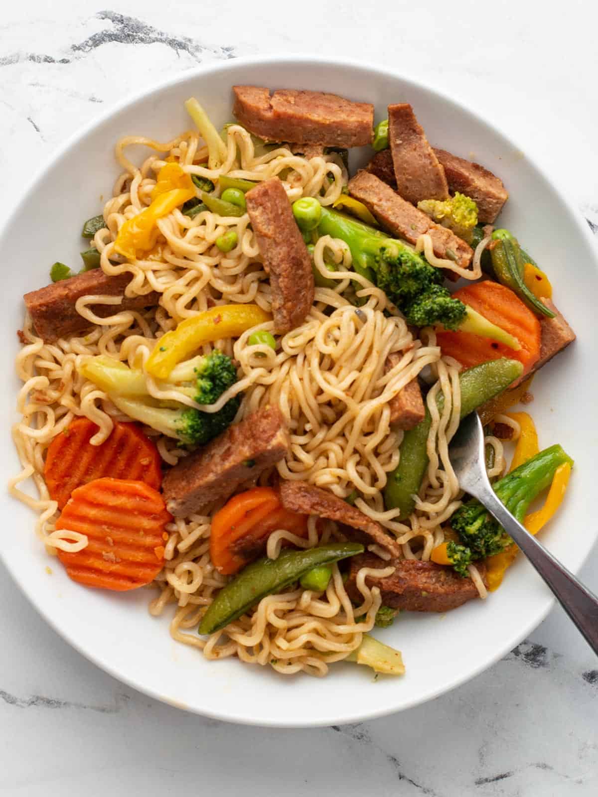 Overhead view of a plate full of spam stir fry with a fork.