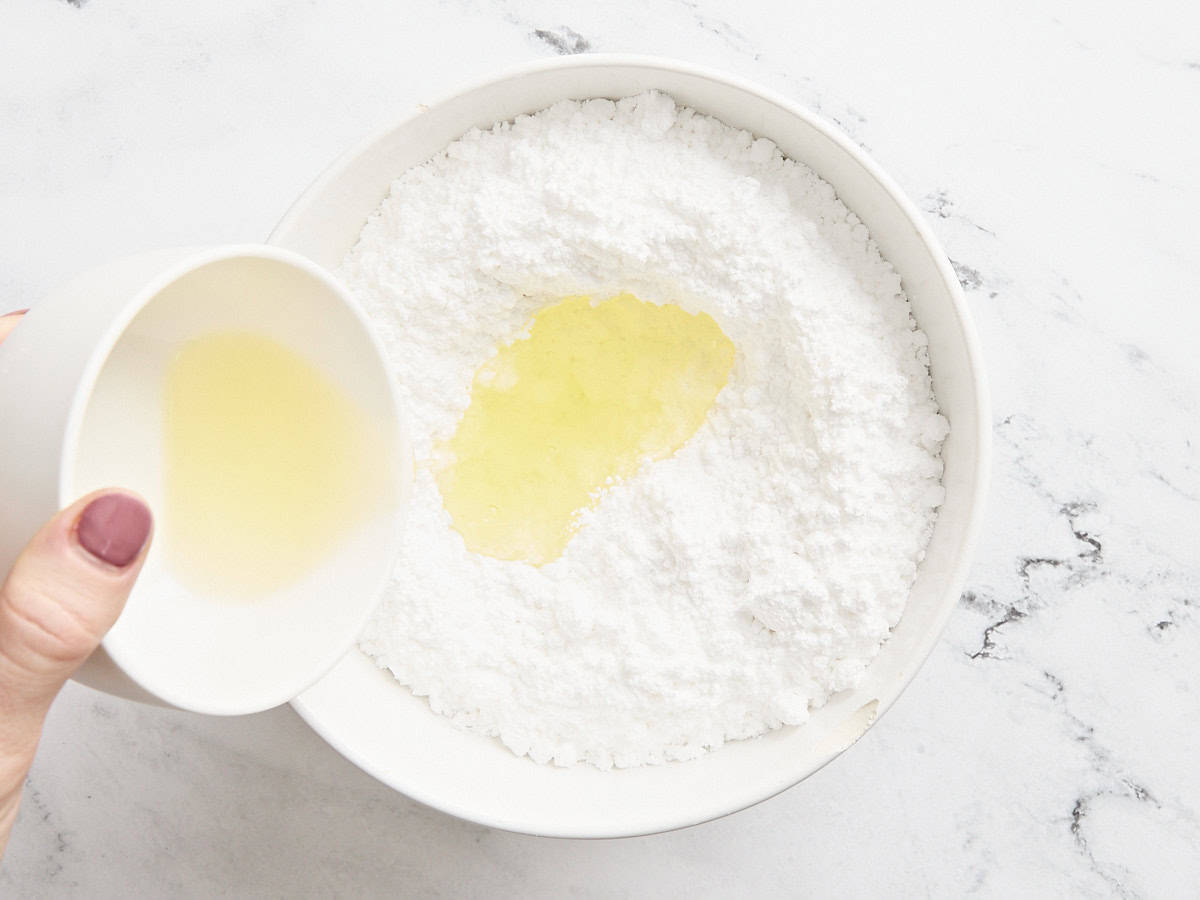 Egg whites added to icing sugar in a bowl.