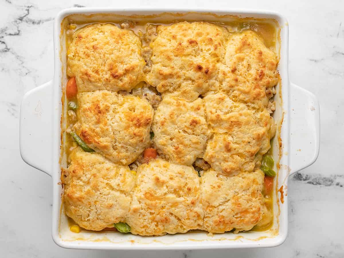 Overhead view of baked chicken and biscuit casserole in a white casserole dish that's ready to be served.