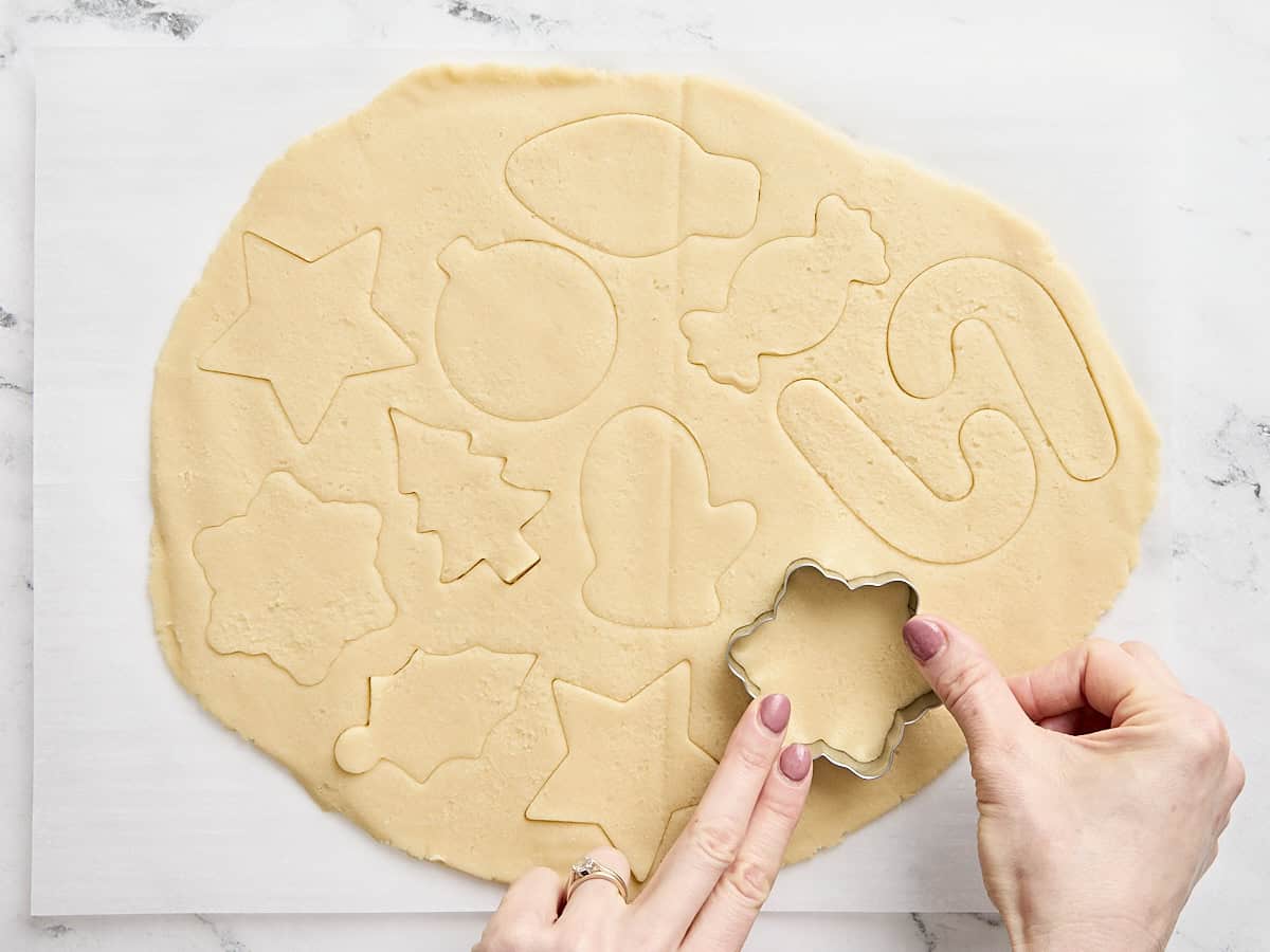 A hand cutting out festive sugar cookies.