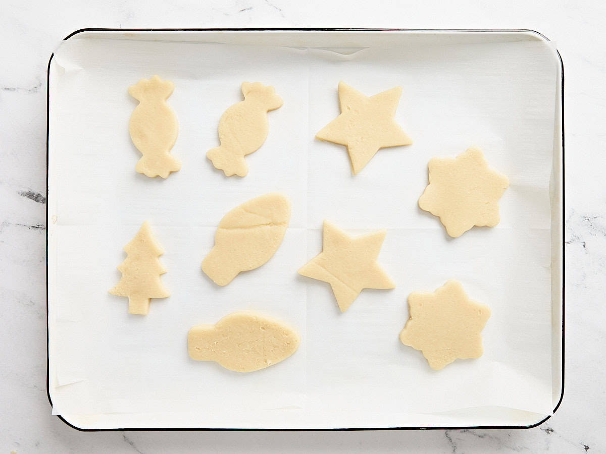 Festive cut out sugar cookies on a parchment lined baking sheet.