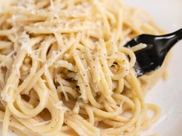 Side shot of finished Cacio e Pepe on a plate with a fork in it.