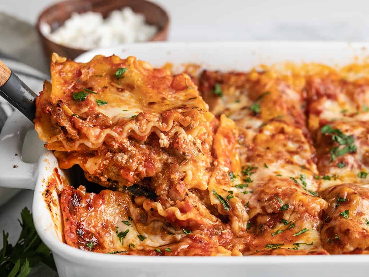 Side view of a slice of lasagna being lifted out of the pan. 