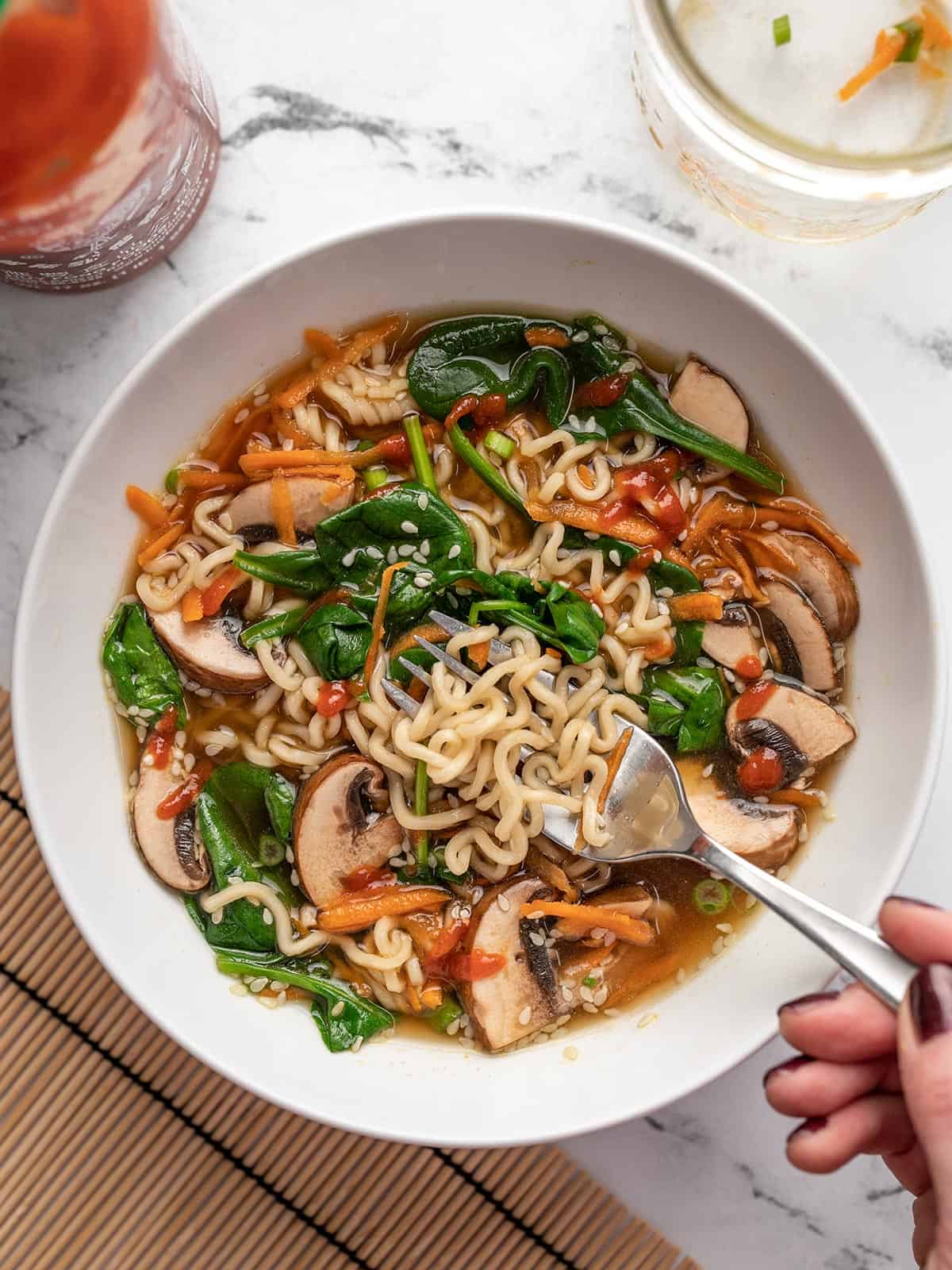 Overhead view of a bowl of noodle soup with sesame seeds. 