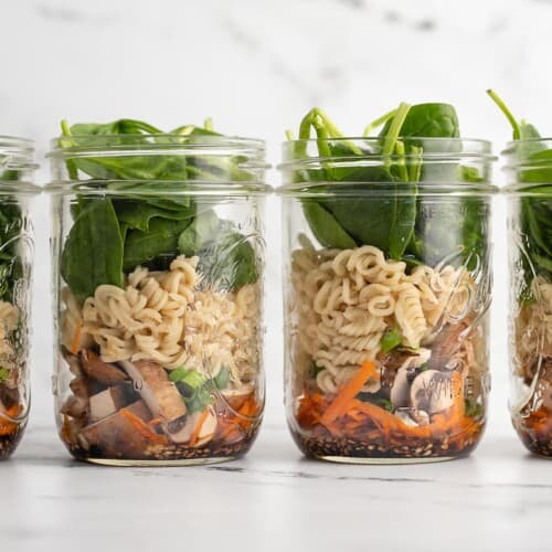 Four noodle soup jars lined up in a row.