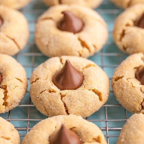 Side view of peanut butter blossoms lined up on a cooling rack.