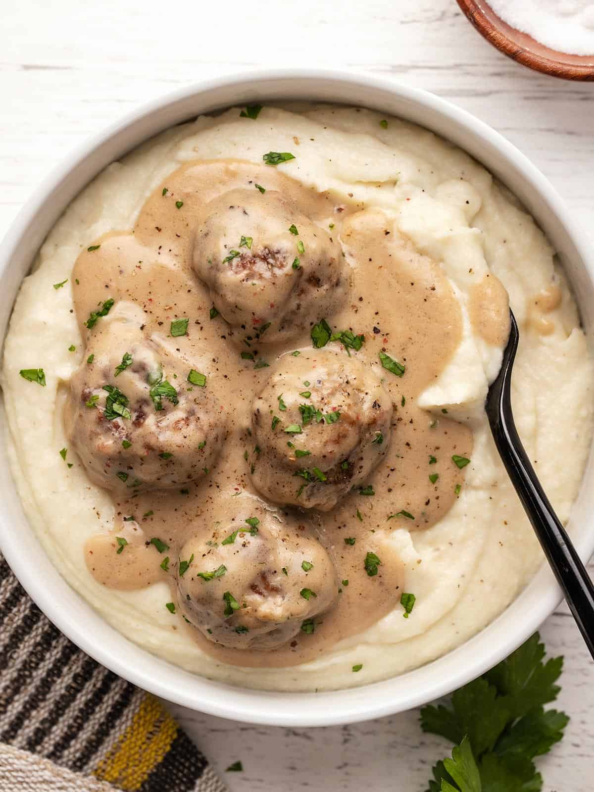 Overhead view of a bowl full of mashed potatoes topped with Swedish meatballs.