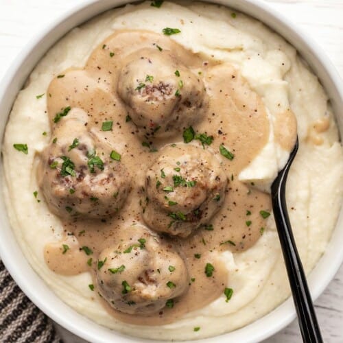 Overhead view of a bowl full of mashed potatoes topped with Swedish meatballs.