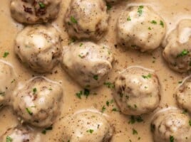 Close up overhead view of meatballs in sauce garnished with parsley.