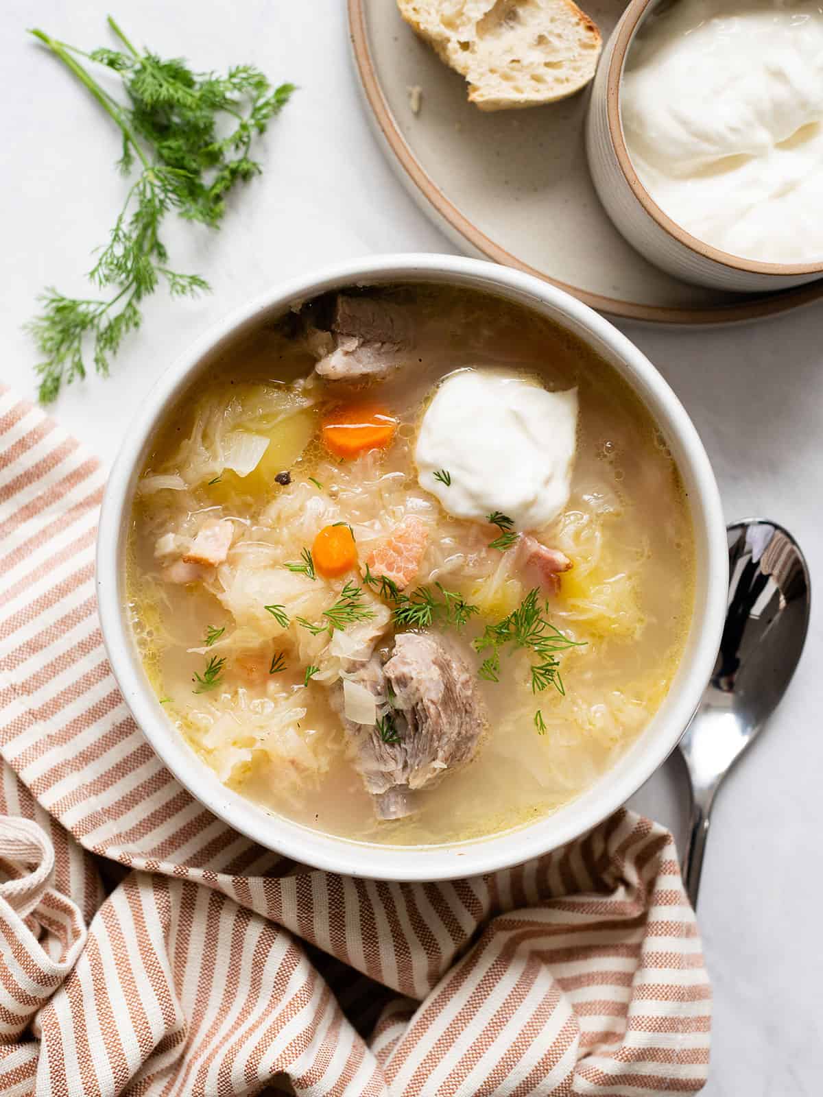 Overhead view of a bowl of kapusniak with sour cream.