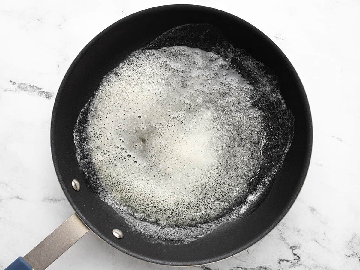 Overhead shot of butter melted and foamed in a pan.