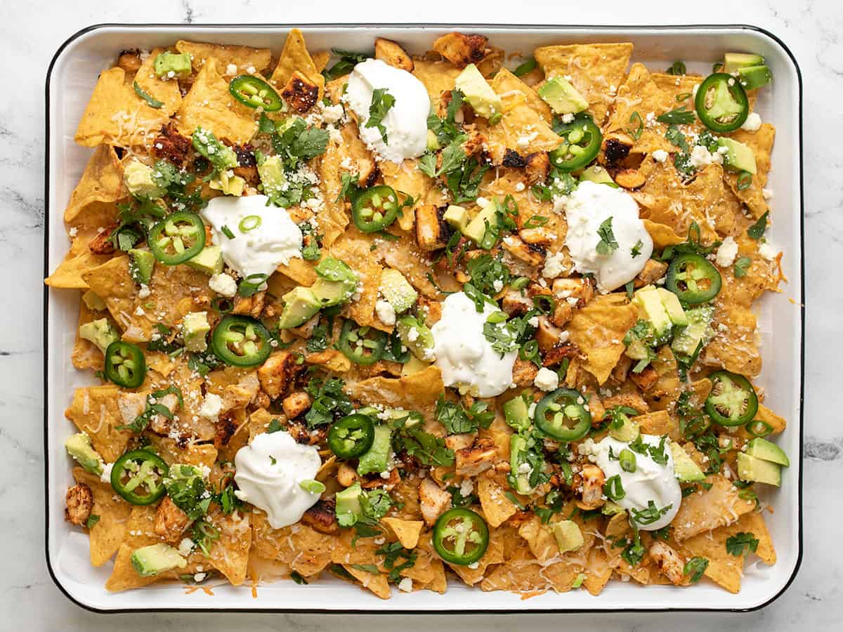 Overhead shot of sheet pan chicken nachos with sliced jalapeño, avocado, and cilantro.