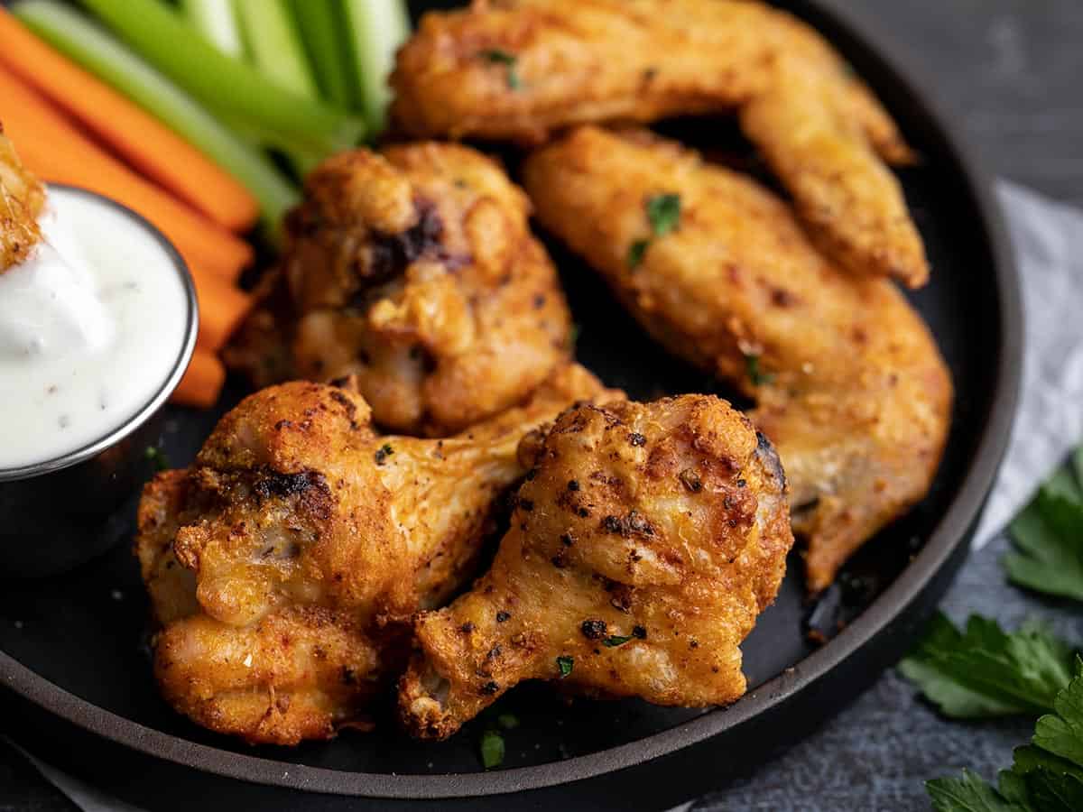 Side shot of air fryer chicken wings on a black plate.