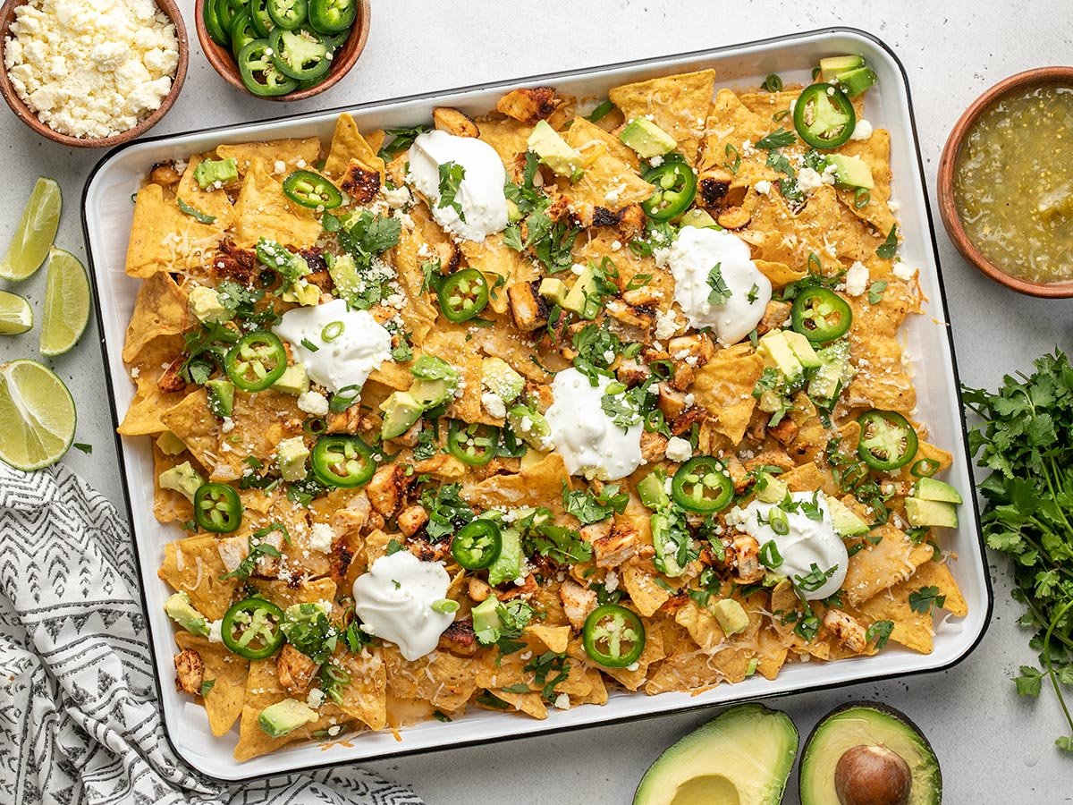 Overhead shot of sheet pan chicken nachos with sliced jalapeño, avocado, and cilantro.