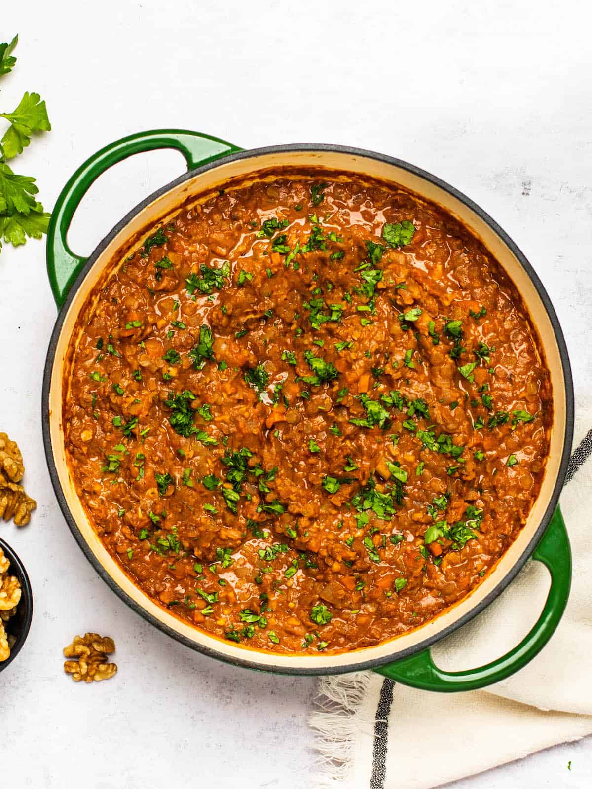 Overhead view of the pot full of lentil bolognese garnished with parsley. 