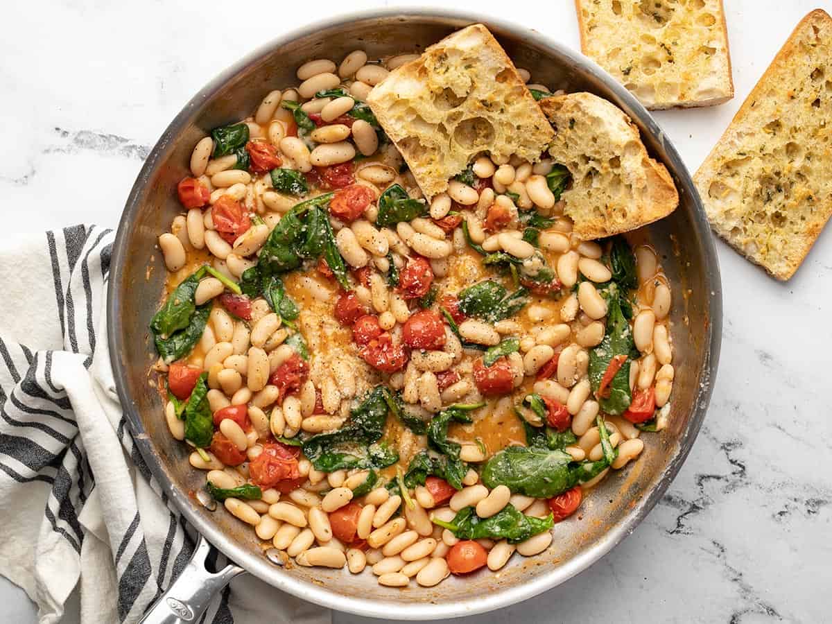 Finished white beans in the skillet with garlic bread in the side.