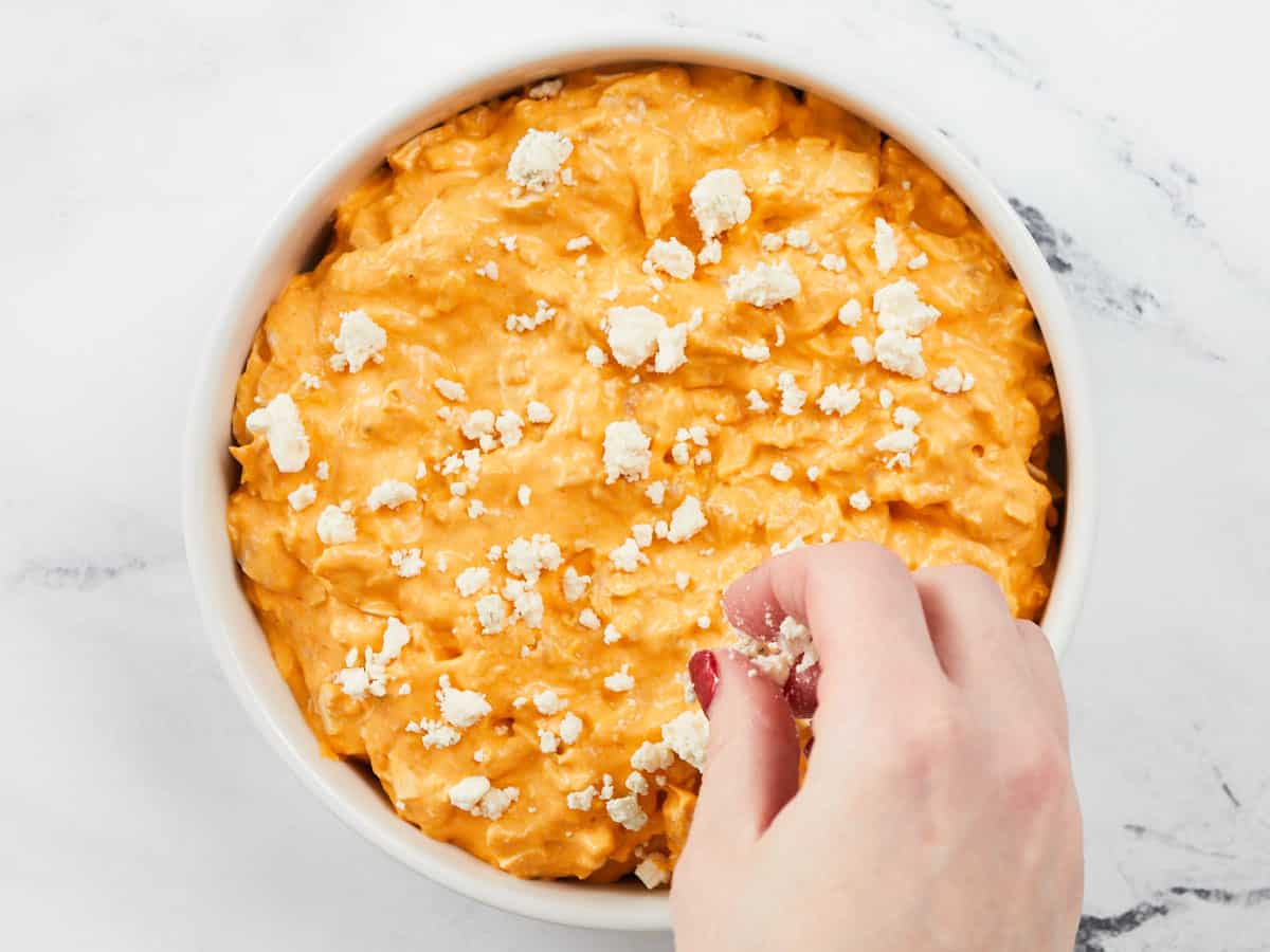 Blue cheese being sprinkled over the dip.