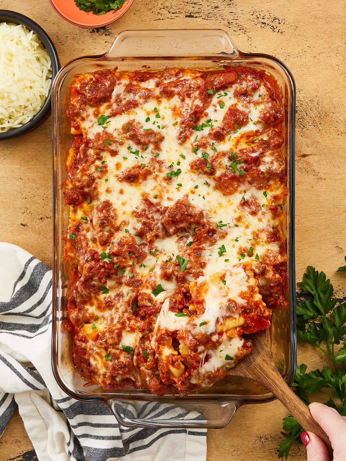 Overhead view of baked ravioli being scooped out of the dish.