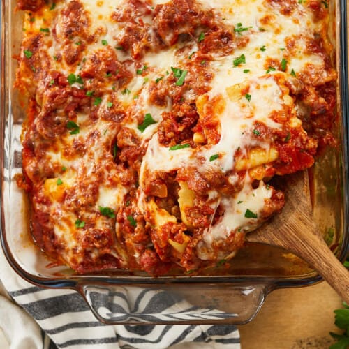 Baked ravioli being scooped out of the baking dish.