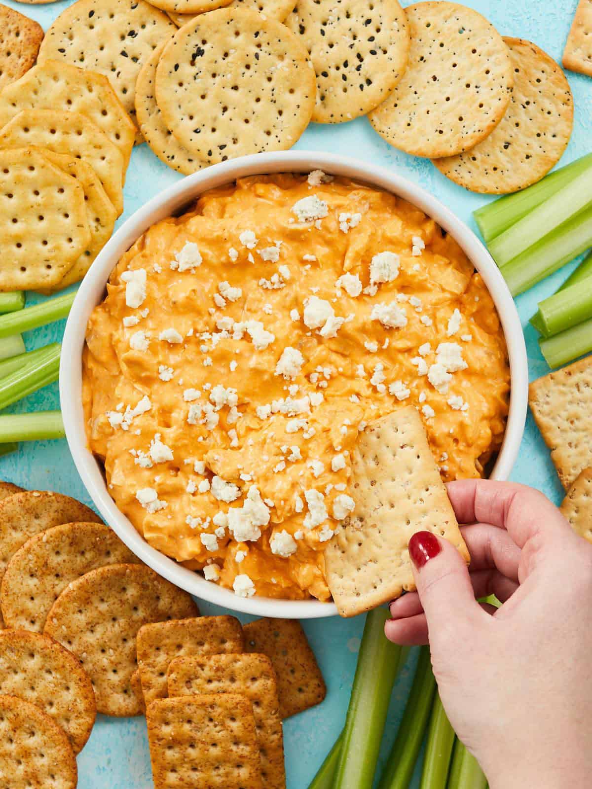 Overhead view of a cracker dipping into a bowl of buffalo chicken dip.