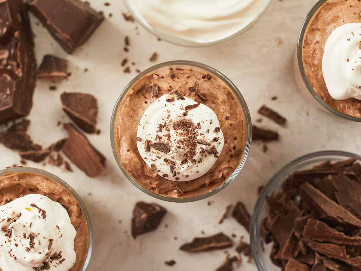 Overhead view of three cups of chocolate mousse with whipped cream and chocolate shavings.