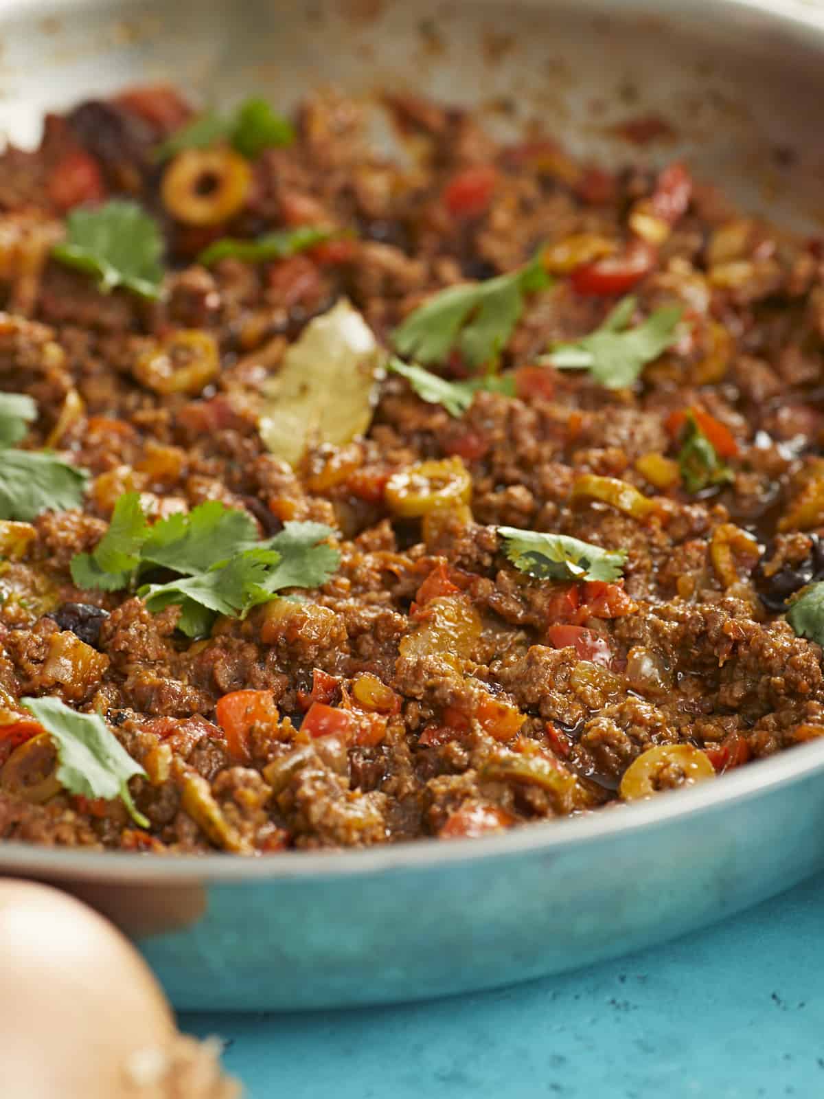 Side shot of picadillo in a silver skillet.