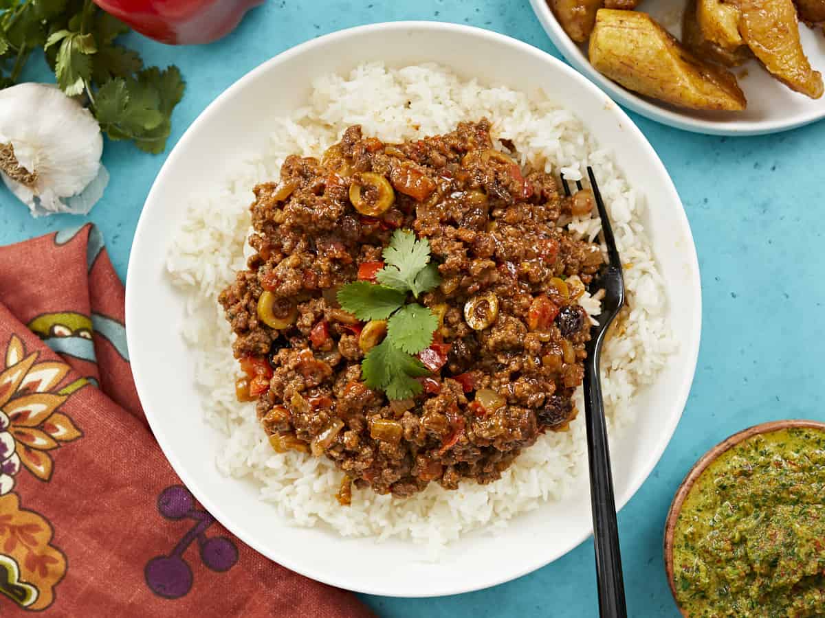 Picadillo served over white rice in a white bowl.