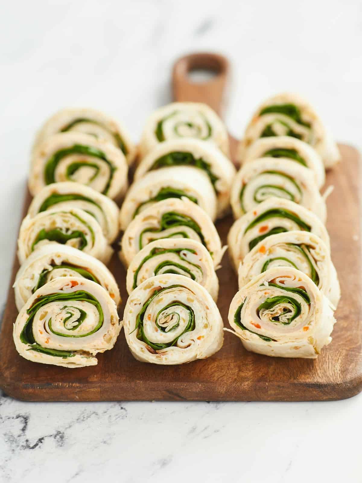 Three rows of pinwheels, each leaning on the one next two it halfway, in three rows placed on a wooden cutting board.