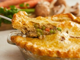 Side shot of a slice of veggie pot pie being removed from the pie dish.